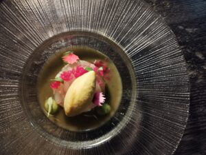 Plato gourmet decorado con flores comestibles y salsa verde