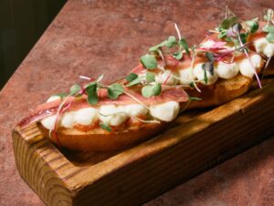 Brioche de anchoas Ortiz con mantequeso y tomate en una tabla de madera