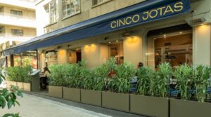 Exterior del restaurante Cinco Jotas en Madrid con plantas decorativas.