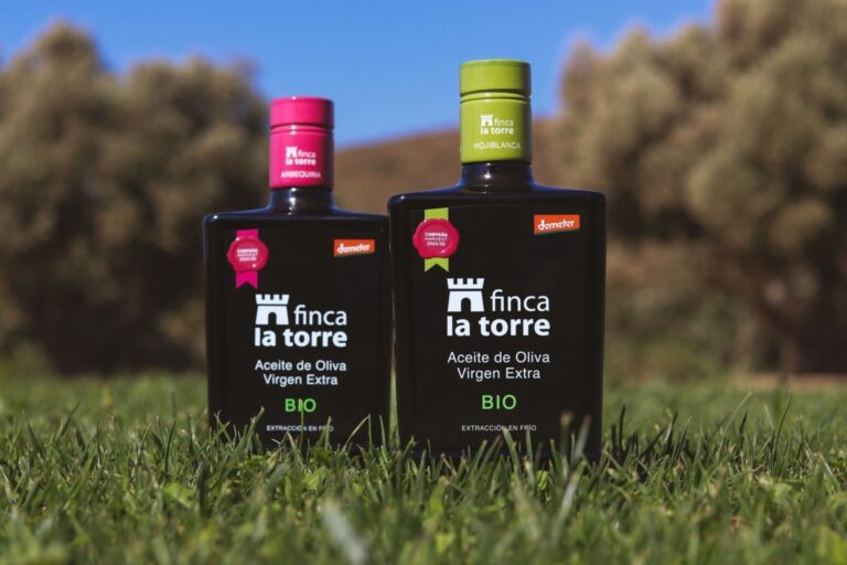 Botellas de aceite de oliva virgen extra de Finca La Torre en un campo.
