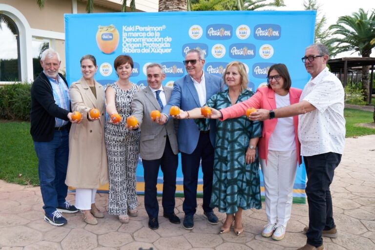 Grupo de personas sosteniendo kakis en un evento promocional.