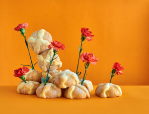 Pan de muerto decorado con flores sobre fondo naranja