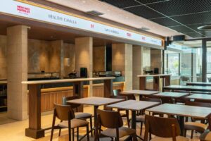 Vista interior del Mercado Madriles Reina Victoria con mesas y barra de comida.