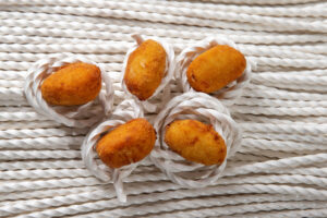 Croquetas doradas sobre fondo de cuerda blanca