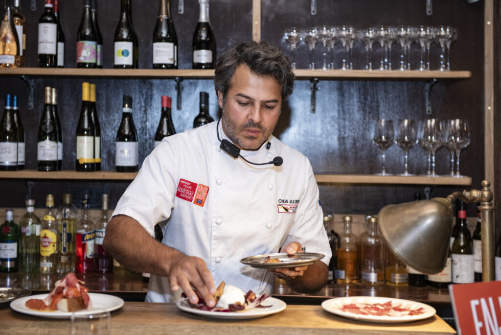 Omar Allibhoy preparando platos con jamón ibérico en un evento culinario.