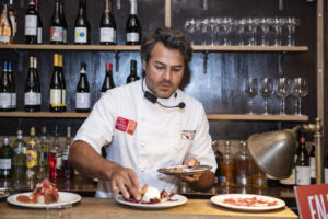 Omar Allibhoy preparando platos con jamón ibérico en un evento culinario.