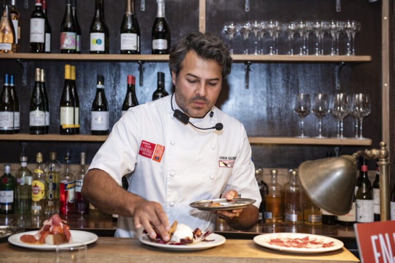 Omar Allibhoy preparando platos con jamón ibérico en un evento culinario.