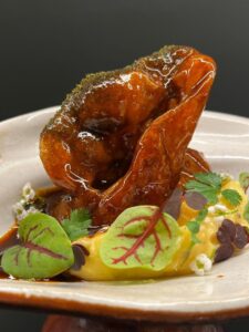 Plato de oreja presentado con salsa y hojas frescas