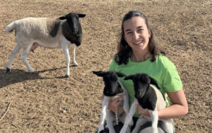 Pilar Pascual sosteniendo dos corderitos en el campo.