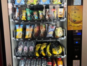 Máquina expendedora con plátanos y snacks en un colegio