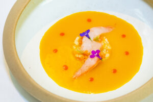 Plato gourmet con gamba blanca, zanahoria escabechada y hinojo decorado con flores.