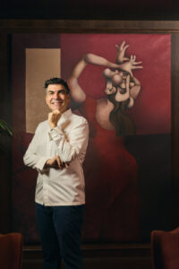 Chef Ramon Freixa posando frente a una obra de arte en su restaurante.