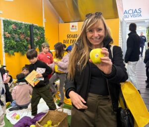 Isabel Aires sosteniendo una manzana en un evento con niños