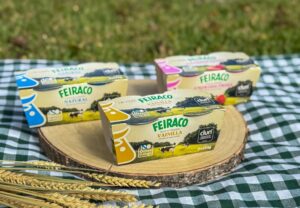 Tres yogures Feiraco de sabores natural, vainilla y fresa sobre una tabla de madera.