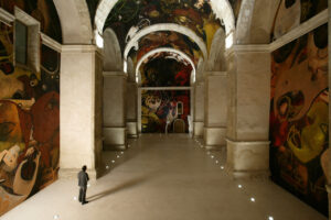 Interior del Centro de Arte con murales coloridos y un visitante