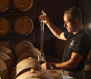 Hombre en bodega sirviendo vino de barrica