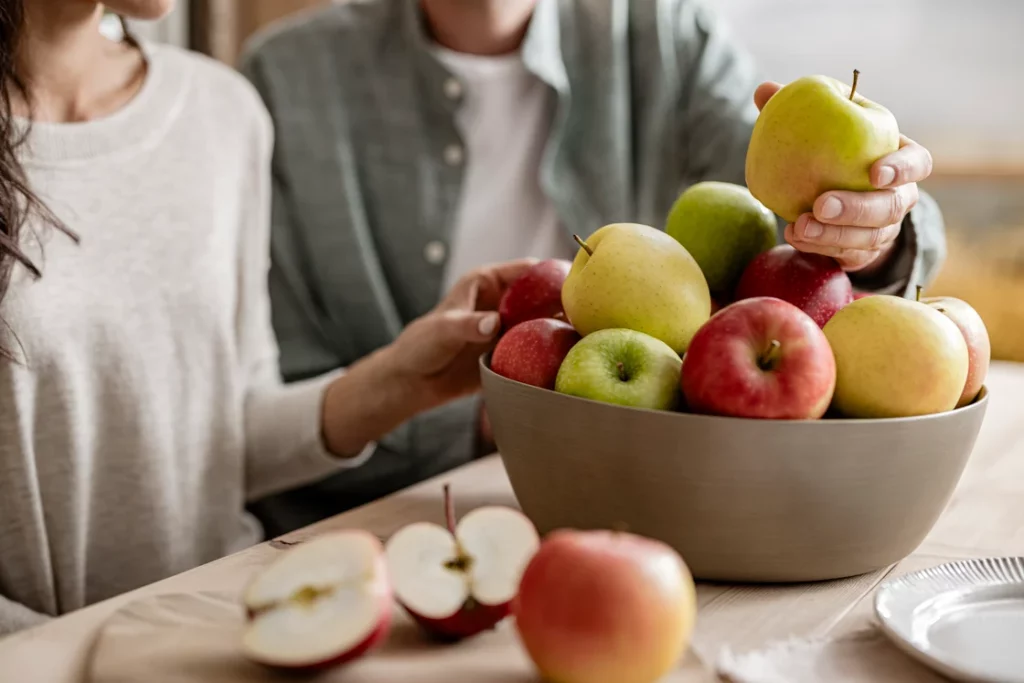 Personas eligiendo manzanas de un tazón en la mesa