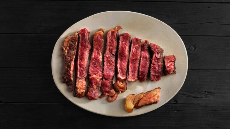 Plato con carne de buey cortada en tiras sobre fondo oscuro.