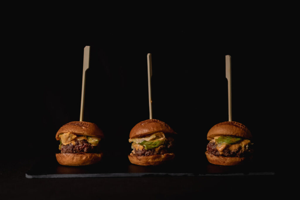Tres hamburguesas con ingredientes frescos en un fondo oscuro