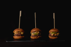 Tres hamburguesas con ingredientes frescos en un fondo oscuro