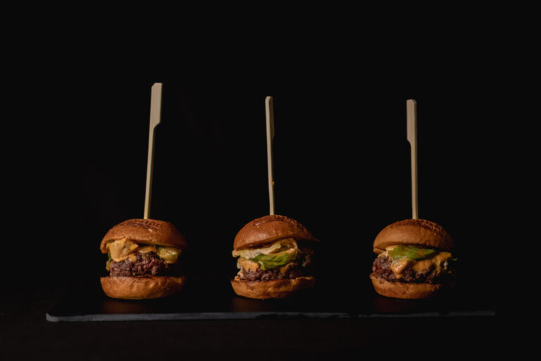 Tres hamburguesas con ingredientes frescos en un fondo oscuro