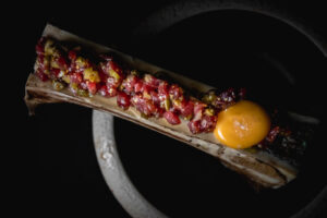 Steak tartar servido sobre un hueso con yema de huevo