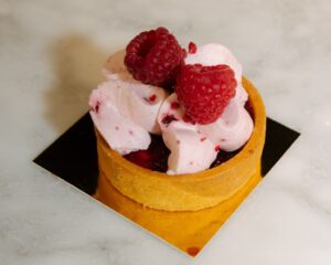 Tartaleta con namelaka de vainilla y chocolate blanco decorada con frambuesas.
