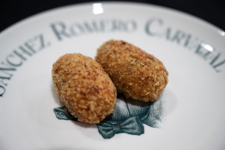 Dos croquetas de jamón ibérico sobre un plato decorativo.