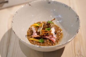 Plato de legumbres con carne y verduras decorativas en un tazón