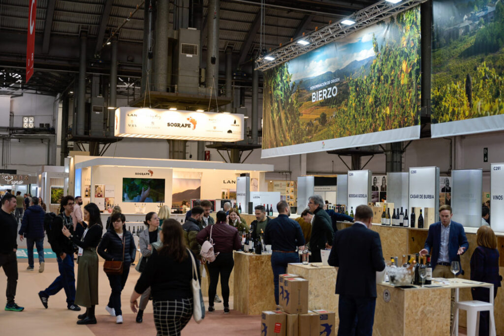 Visitantes en la feria de vino en Barcelona, con stands de bodegas.