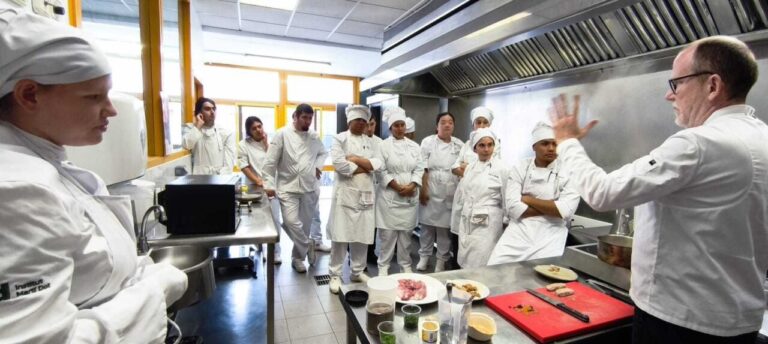 Estudiantes de cocina escuchando a un instructor en una escuela de hostelería