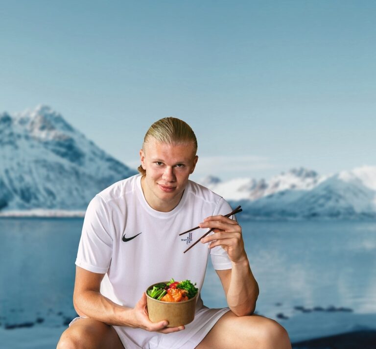 Erling Haaland disfrutando de un plato con salmón noruego en un paisaje montañoso.
