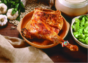 Lechazo asado servido en un plato de barro con guarnición.