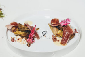 Plato gourmet con jamón ibérico y alcachofas decorado con flores