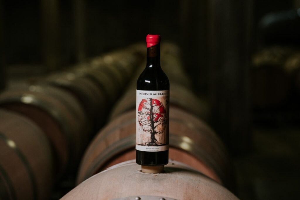 Botella de vino Dominio de Elbio sobre barricas de madera