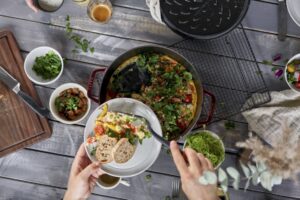 Plato servido con comida fresca y pan junto a una cazuela Staub