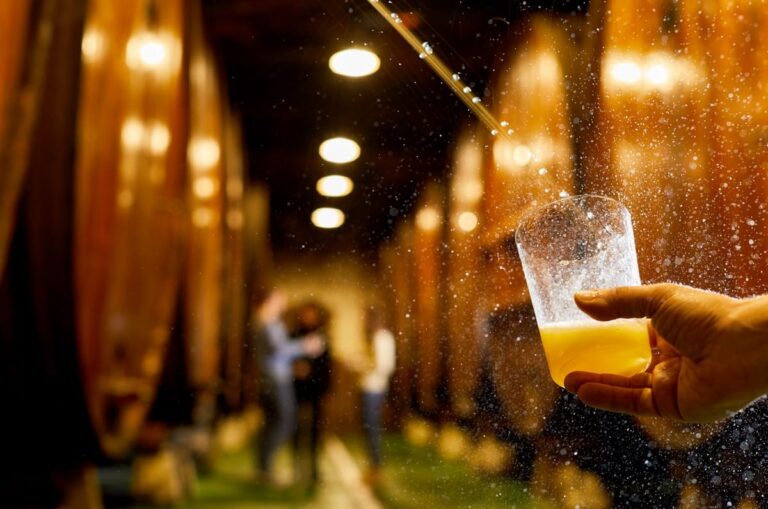 Una mano sostiene un vaso de sidra en una sidrería