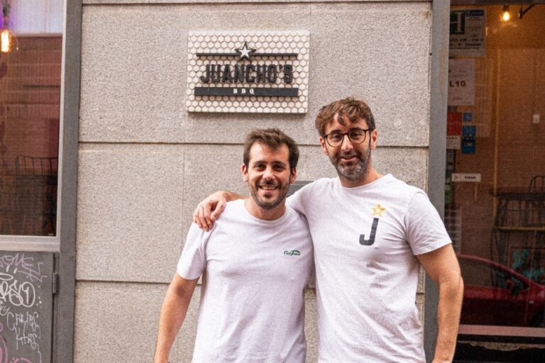 Dos chefs sonrientes frente al restaurante Juancho's BBQ en Barcelona