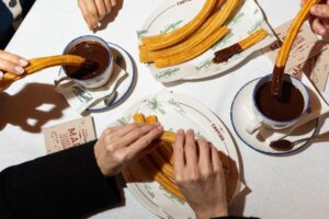 Manos disfrutando chocolate con churros en San Ginés