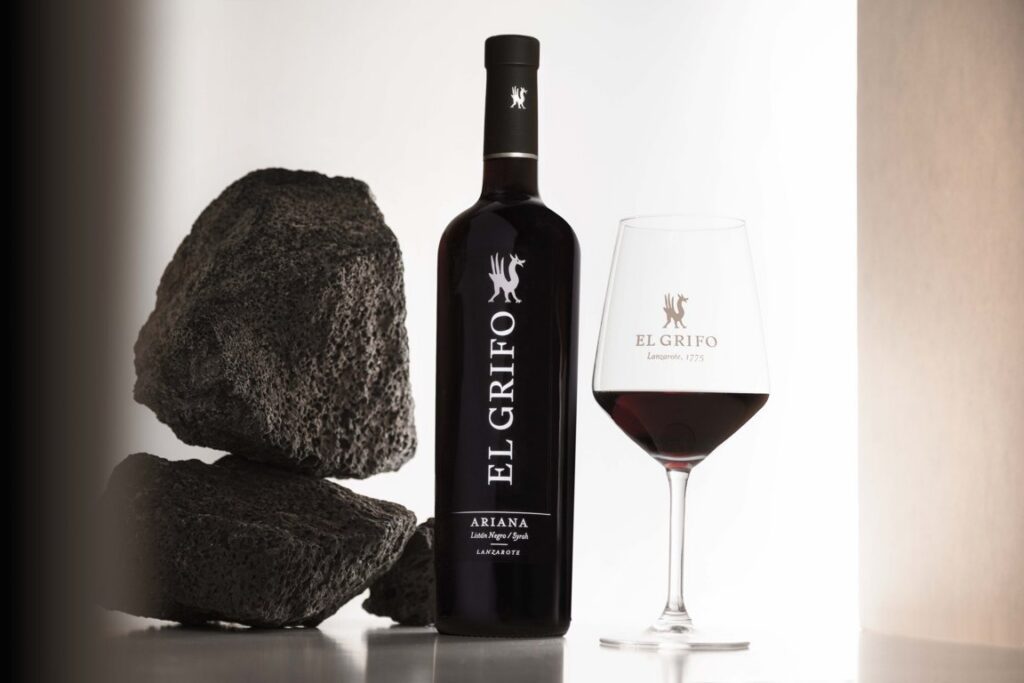 Botella de vino El Grifo Ariana 2024 junto a una copa y piedras volcánicas