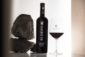 Botella de vino El Grifo Ariana 2024 junto a una copa y piedras volcánicas
