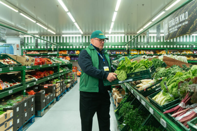 Empleado de Makro seleccionando verduras frescas en el supermercado
