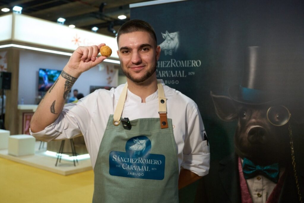 Chef Alejandro Cano sosteniendo una croqueta en un evento gastronómico