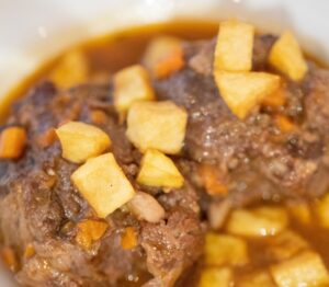 Plato de rabo de toro estofado con trozos de patata frita