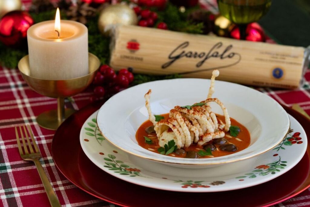 Plato de pasta Garofalo con decoración navideña y vela encendida