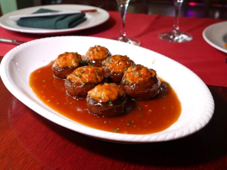 Champiñones rellenos de langostinos con salsa cantonesa en un plato.