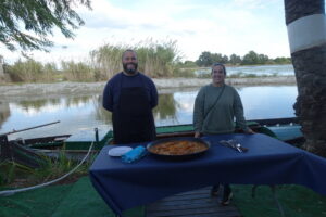 Dos personas junto a una mesa con paella en el Parque Natural de l'Albufera