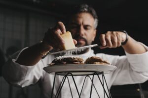 Chef Salvatore Romano preparando un plato con queso rallado