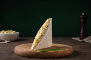 Sándwich de huevo presentado sobre una tabla de madera