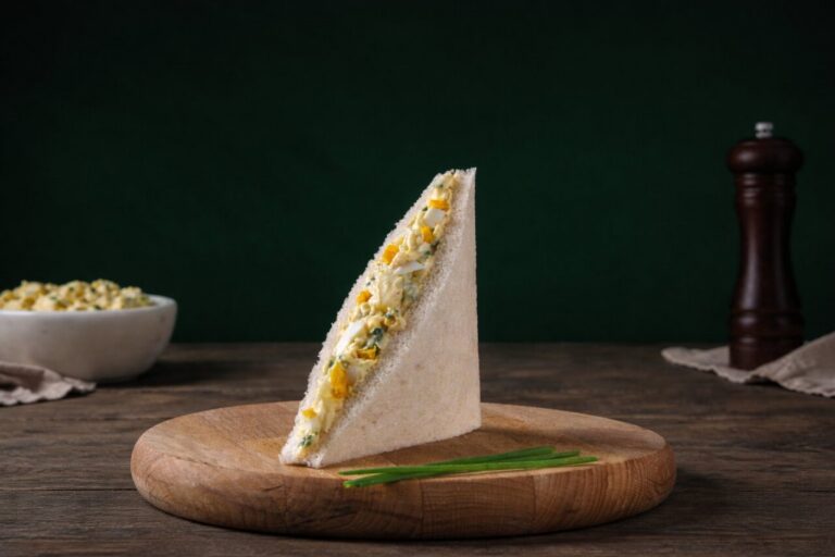 Sándwich de huevo presentado sobre una tabla de madera